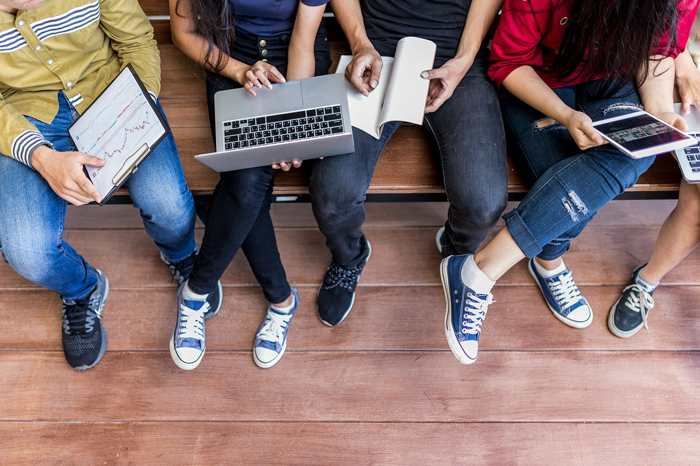 top down of teens sitting using technology